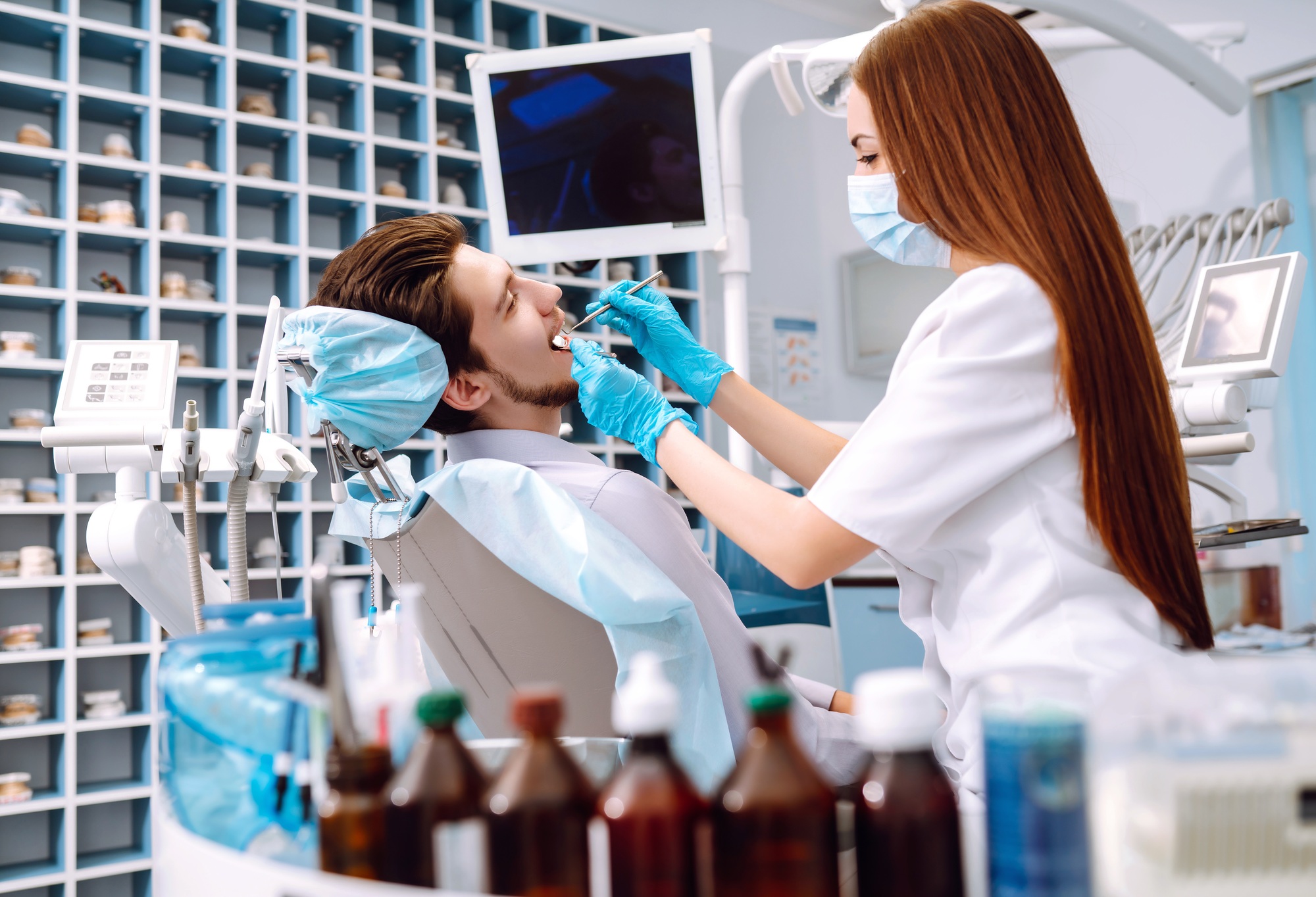 Young man at the dentist's chair during a dental procedure. Overview of dental caries prevention.